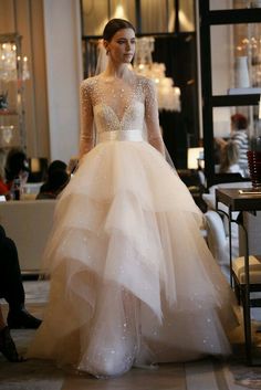 a woman in a wedding dress is walking down the runway