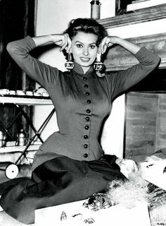 black and white photograph of a woman sitting on the floor with her hands behind her head