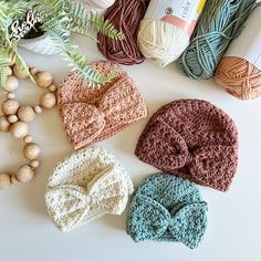 several crocheted hats and balls of yarn on a table next to some beads