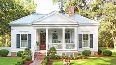 a white house with blue shutters and a dog in the front yard