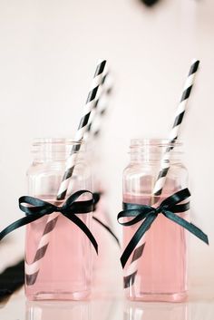 two mason jars with black and white striped straws in them, tied with ribbon