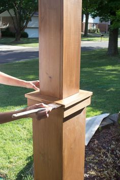 a person holding an object in their hand near a tall wooden structure on the grass