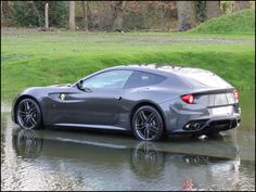 a grey sports car is driving through some water