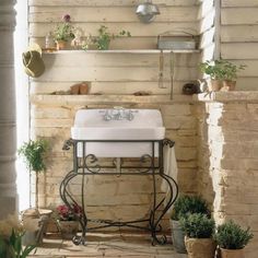 a white sink sitting on top of a metal stand next to potted planters