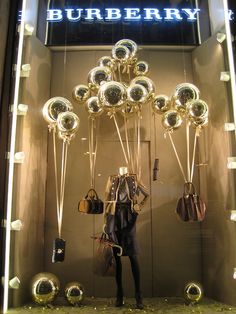 a burberry window display with handbags and purses hanging from the front