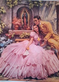 an image of a man and woman in pink dresses sitting next to each other on the ground