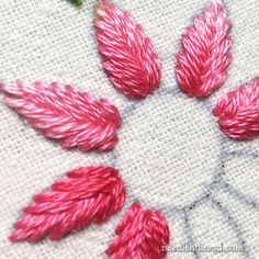 some pink flowers are on a white table cloth with green leaves in the center and one is red