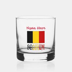 a shot glass with the name here and belgium in red, black, yellow, and green