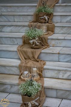 three vases filled with baby's breath sitting on top of some stone steps