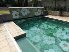 an outdoor swimming pool with flowers painted on the side and tiled flooring around it