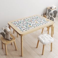 a wooden table and two stools with an elephant stuffed animal on the floor next to it