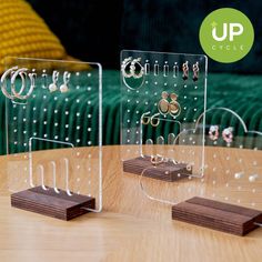 three clear acrylic displays on top of a wooden table with rings and earrings