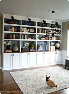 a living room filled with lots of white bookshelves