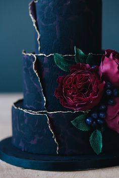 a three tiered cake with purple and red flowers