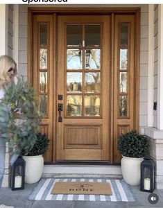 a woman walking into a front door with potted plants