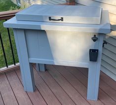 a blue bench sitting on top of a wooden deck next to a house with a potted plant