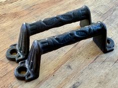 two black metal handles sitting on top of a wooden floor