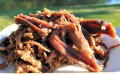 a white plate topped with meat covered in gravy next to a green field