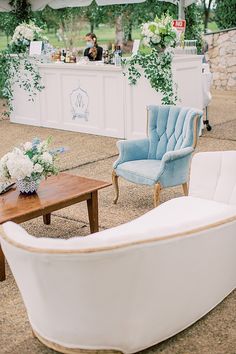 two chairs and a table with flowers on it in front of a white tent at an outdoor event