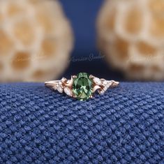 a ring with an oval green stone surrounded by small white diamonds on a blue cloth