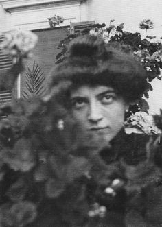 an old black and white photo of a woman with flowers in front of her head