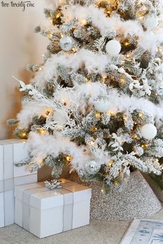 a white christmas tree with presents under it