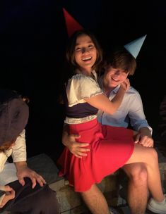 a man and woman sitting next to each other with a party hat on their head