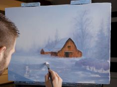 a man is painting a barn in the snow with a brush and watercolor pencil