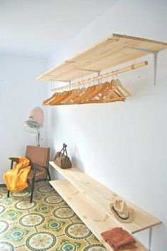 a room with a bench, chair and hat hanging from it's hooks on the wall