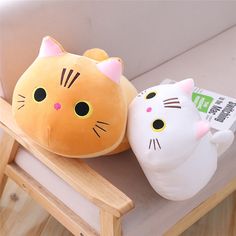 two stuffed cats sitting on top of a wooden chair