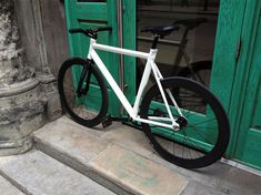 a white bicycle parked in front of a green door