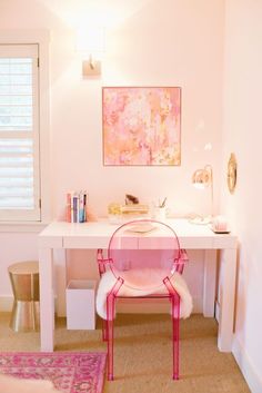 a pink chair sitting in front of a white desk