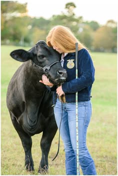 a woman in jeans holding a black cow with a measuring tape around it's neck