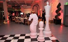 two large white chess pieces sitting on top of a black and white checkered floor