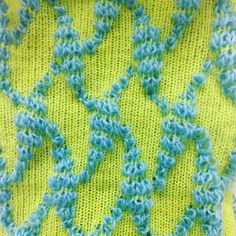 a green and blue crocheted blanket with wavy lines