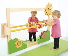 two children playing with wooden toys in front of a mirror