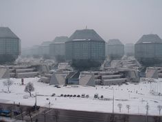 an aerial view of a city with snow on the ground and buildings in the background