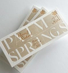 three white and gold business cards with palm trees on the front one is for spring