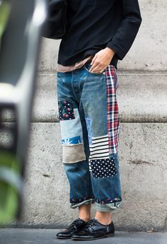 a person standing in front of a wall wearing ripped jeans