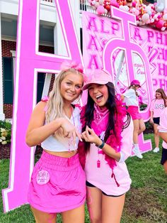 two women in pink outfits standing next to each other near a large sign that says 4