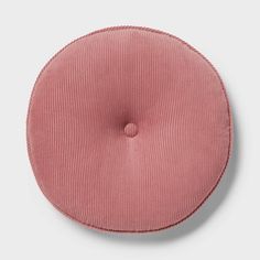 a pink round cushion sitting on top of a white wall