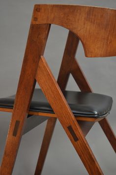 a close up of a wooden chair with black leather seat pad and backrests