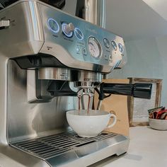 an espresso machine sitting on top of a counter next to a white bowl