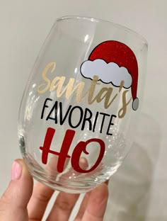 someone holding up a wine glass that says santa's favorite ho