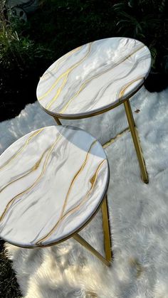 two marble tables sitting on top of a white rug