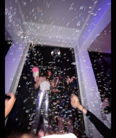 people are throwing bubbles in the air at a party with confetti on the ceiling