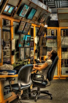 a man sitting at a computer desk with lots of monitors