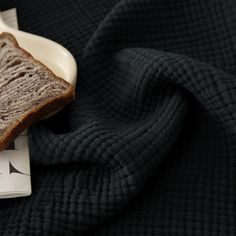 a piece of bread sitting on top of a white plate next to a black towel