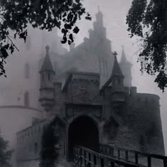 an old castle is surrounded by fog and trees