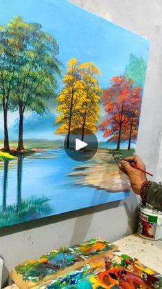 a man is painting trees on a canvas